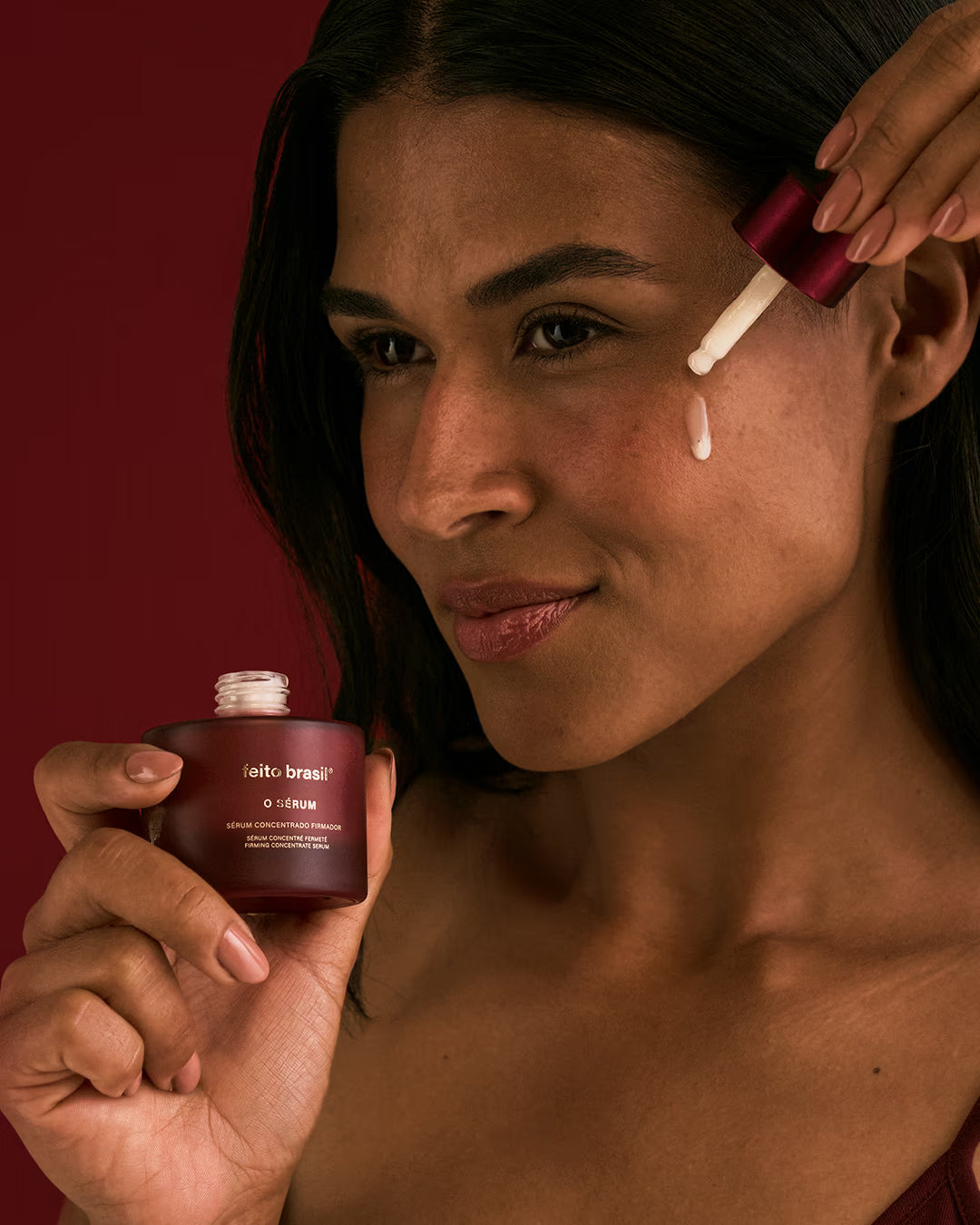 Mulher aplicando gotas do Sérum Facial Firmador no rosto demonstrando o ritual de skincare.