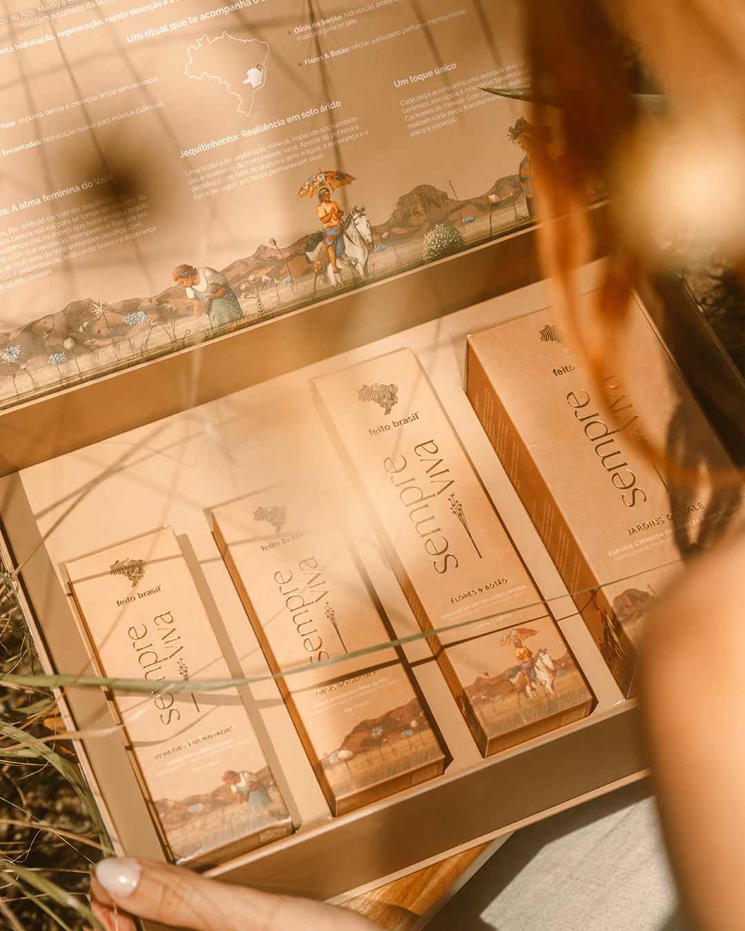 Caixa de presente da feito brasil inspirada nas sempre-vivas com produtos artesanais de luxo e mulher recebendo o presente.