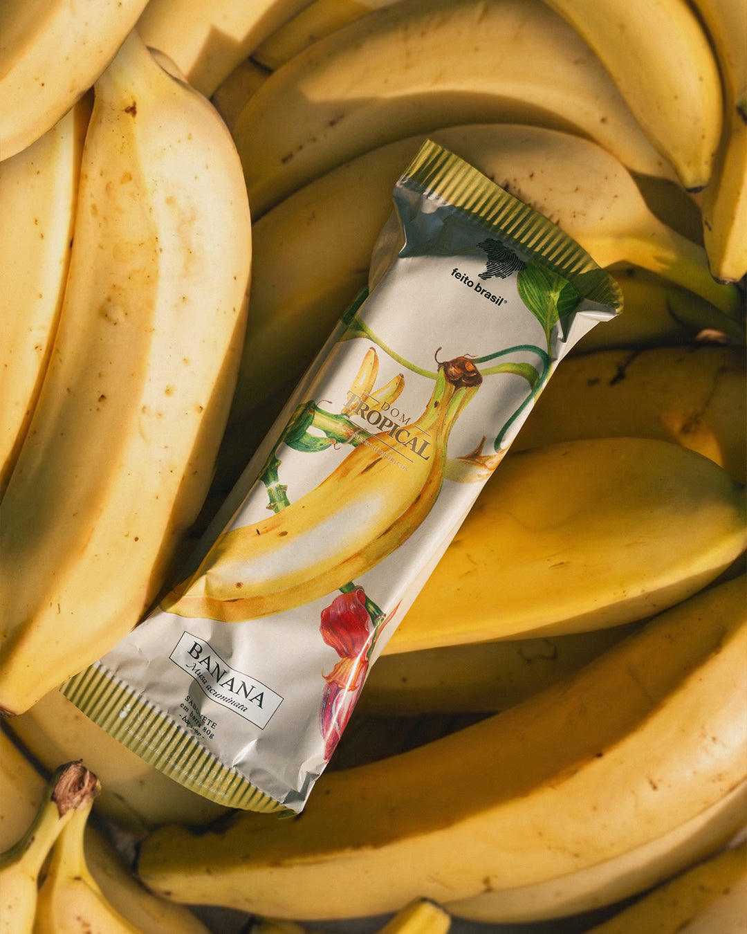 Premiado sabonete em formato de picolé Dom Tropical da marca feito brasil sobre bananas maduras.