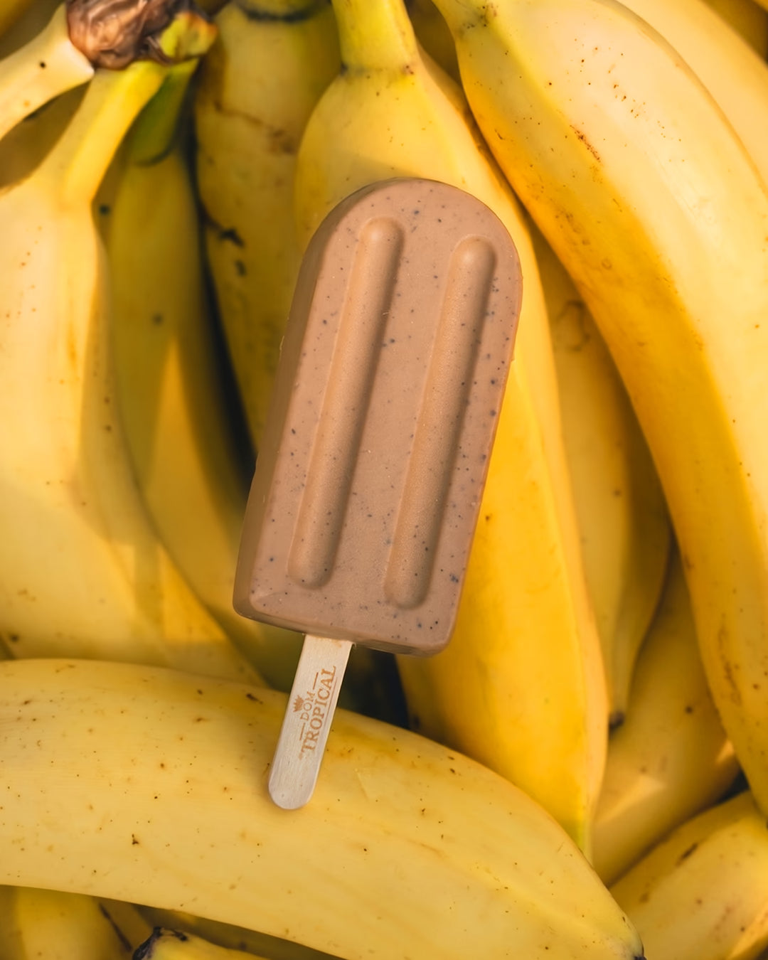 Sabonete em barra luxuoso em formato de picolé sobre bananas maduras.